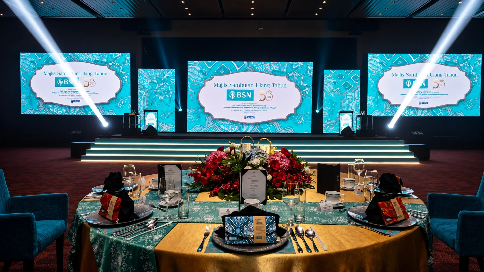 BSN gala dinner setup with three LED screens on stage and floral centrepiece table